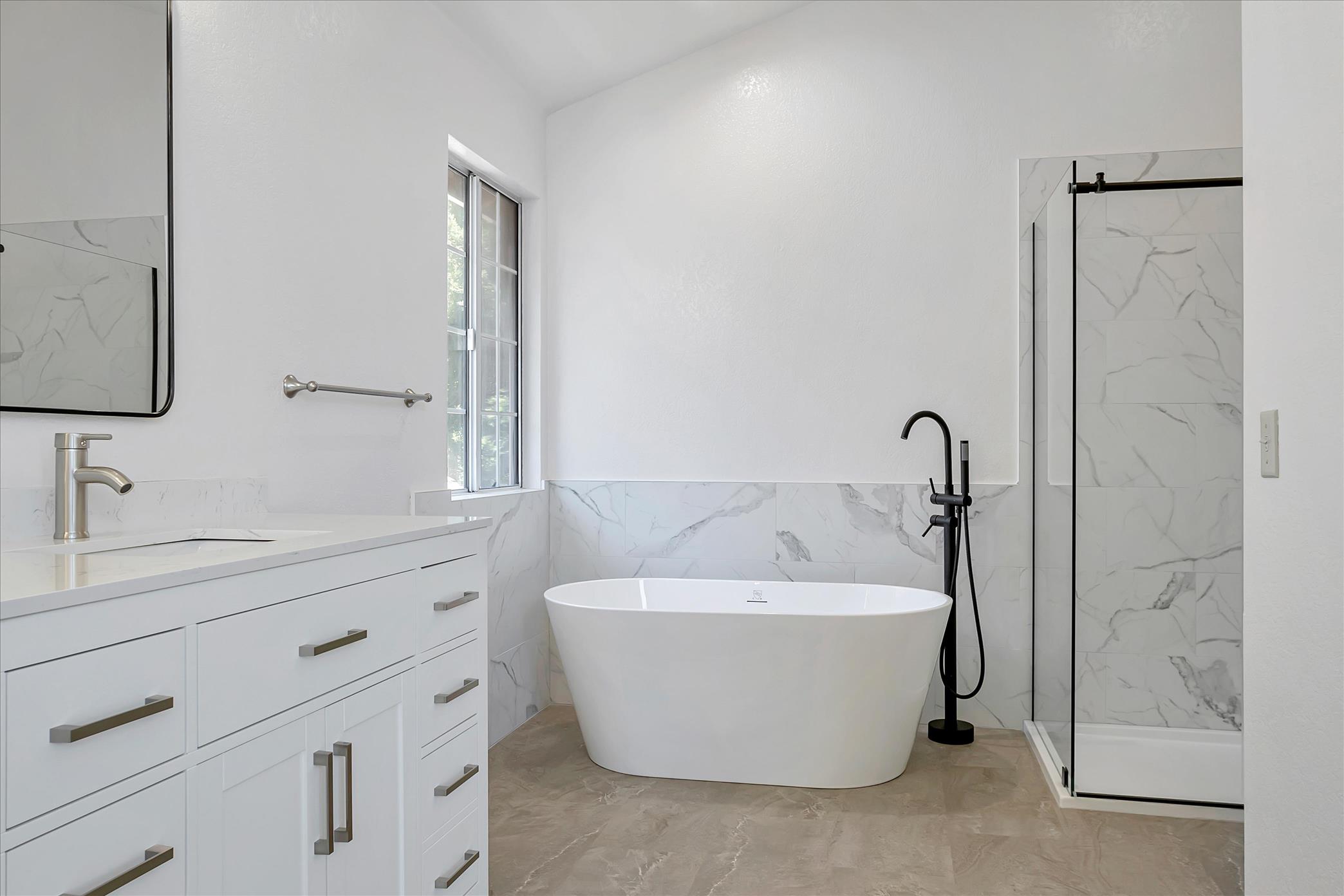 Freestanding tub and marble-look tile in a remodeled Danville bath.