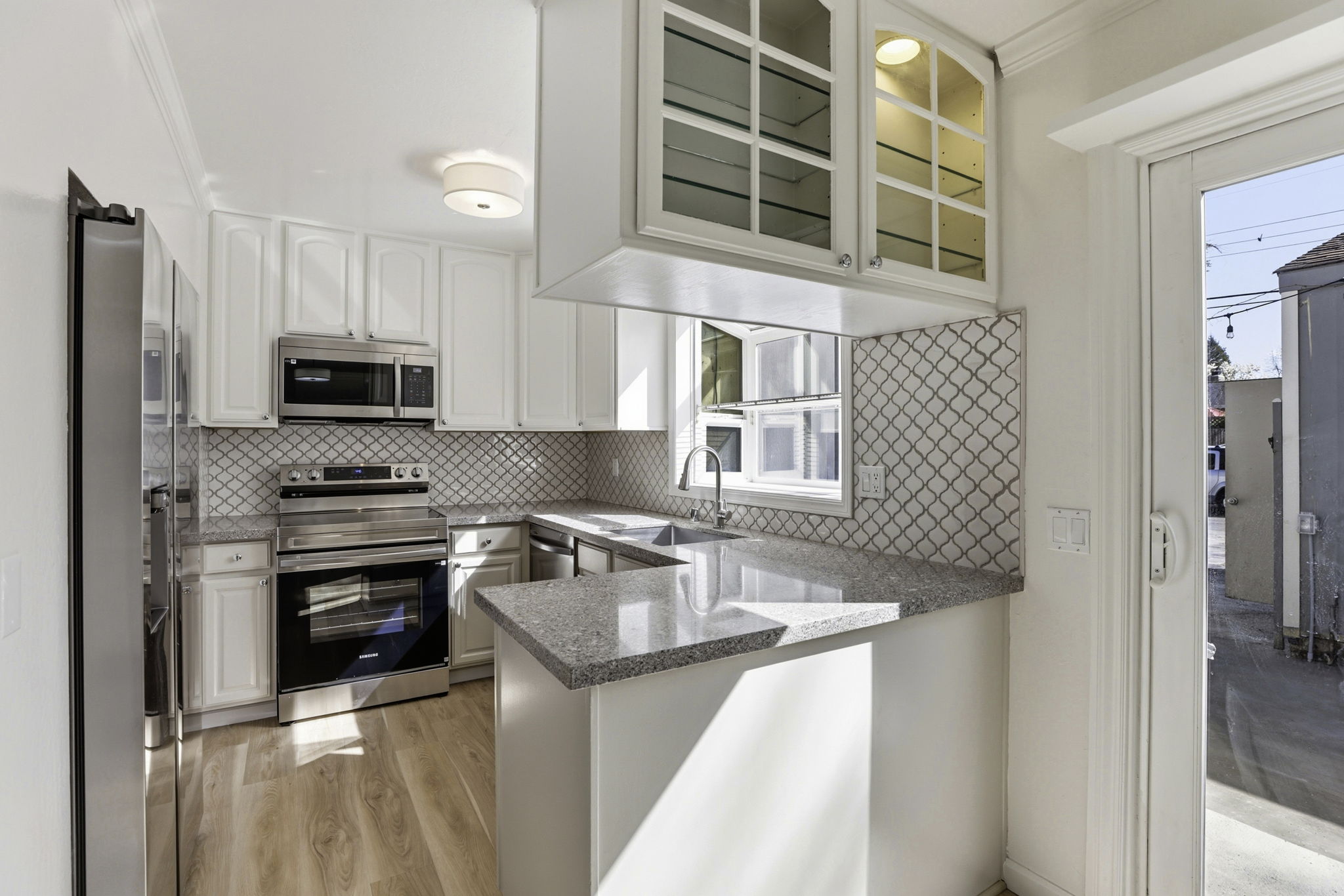 The same kitchen after the remodel, with quartz counters and stainless appliances.